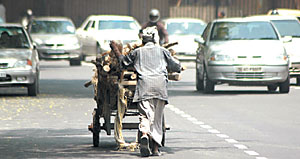 A worker pushes a cart loaded with wood on a busy city road on International Labour Day in the Capital.