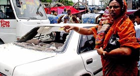 A woman laments after her car is damaged by activists during an Opposition protest in Dhaka on Tuesday