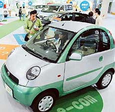A visitor tries sitting behind the wheel of Toyotas mini electric vehicle at a showroom in Tokyo on Wednesday.
