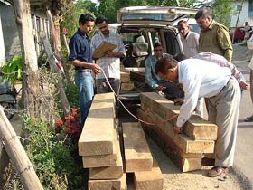 Forest officials measure the smuggled timber that was seized near Sundernagar