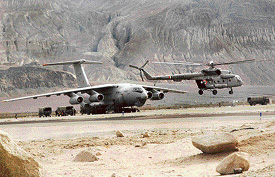 A Mi-17 V1 helicopter, with its rear ramp removed to facilitate para drops, takes off for a sortie as troops board an IL-76 in the foreground at Thoise airfield in northern Jammu and Kashmir.