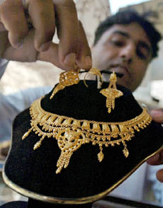 A Pakistani jeweller places a gold earring with a necklace on display at a shop in Karachi on Friday. 