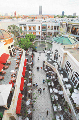 Shoppers walk down a street lined with restaurant at The Grove outdoor shopping mall in Los Angeles.
