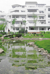 A man crosses a footbridge over a body of water reflecting new Mediterranean-style homes being developed on the outskirts of Beijing.