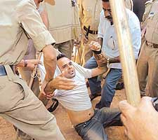 Policemen drag a medical student during a protest rally against the proposed OBCs quota in central educational institutes in Bangalore on Sunday.