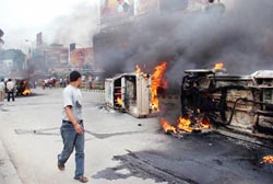 A Nepali walks past torched vehicles at Thapathali in Kathmandu