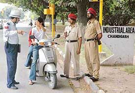 Punjab Police cops look on as a Chandigarh Traffic policeman points out a traffic violation to a two-wheeler rider near the Industrial Area in Chandigarh on Wednesday.