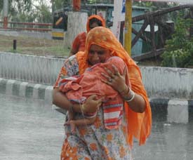 A woman runs for shelter in an effort to protect her child from rain in Ludhiana on Friday