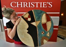 Ms Catherine Mansan, Head of Christies Public Relations in Europe and West Asia, displays an art work by Farid Belkahia of Morocco prior to Christies first public modern and contemporary art sale in Dubai on Sunday