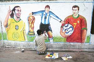 An artist paints images of football stars on a wall in Kolkata on Monday.