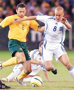Australian player Josip Skoko contests the ball with Greek player Stylianos Giannakopoylos during their football match played in Melbourne on Thursday