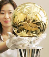 A woman shows off a soccer ball made of pure gold 