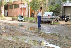 A man treads carefully through a pool of water in front of the showroom where he works in Phase I, Industrial Area, Chandigarh