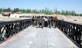 Army officers inspect a reconstructed bridge, connecting Gulmarg with Srinagar, before its inauguration in Baramula