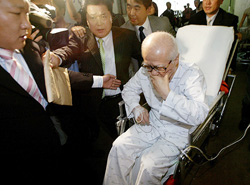 Kim Woo-choong (right), founder of Daewoo Group, sits on a wheelchair as he leaves a court in Seoul 