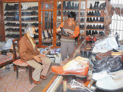 Peter Tatung shows genuine leather shoes to a customer in his shop on The Mall.