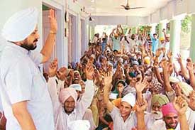 Residents of Jhumba Bhaika village raise their hands in protest against the alleged encroachment on a widows land at the village, near Bathinda, on Wednesday.
