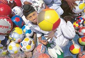 A youngster gets into the spirit of World Cup by posing with  footballs being sold along the Chandigarh-Delhi highway on Sunday.