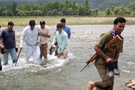 Jammu and Kashmir Peoples Conference Chairman Sajjad Gani Lone crosses a river with party supporters to reach the main market of Kupwara during a curfew