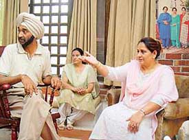Surinder Kaurs daughter, Dolly Guleria, remembers her mother as the relatives look on. In the backdrop is the portrait which represents three generations of singers in the family
