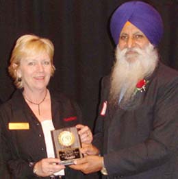 Dr Raghbir Singh Bains accepts the award from Karla Pearson, Director, The Leader News Group, in Surrey, Canada