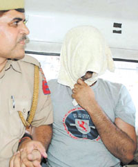 Sub-Inspector K. B. Jha, with face covered, who was arrested for raping a bar girl in the Capital