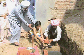 A girl performs a brick-laying ceremony at Otalan village near Samrala.