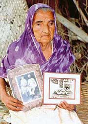 A file photo of Sarjeet Kaur, an INA veterans wife, with photos of her husband and son.