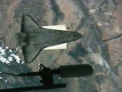 The space shuttle Discovery performs a pitch manoeuvre as crew members aboard the international space station conduct a photo survey