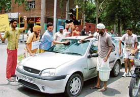 Members of the Unemployed PTI Teachers' Union wash a car in protest against government apathy towards their demands in Sector 17, Chandigarh, on Friday