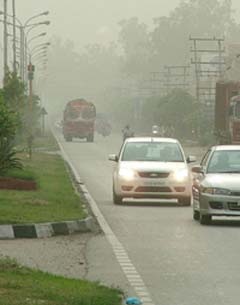 Vehicles cut through a thick blanket of dust on the roads of Jalandhar