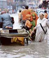 People make their way in street flooded with water during a heavy rain, in Amritsar on Sunday.