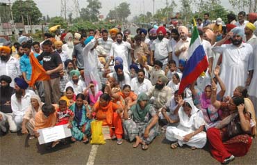 Family members of Sanjiv Kumar and Gurwinder Singh block the GT road near BSF Chowk, Jalandhar, on Monday.