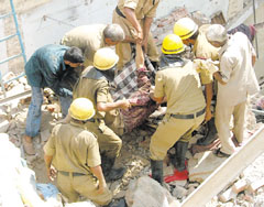 Firemen carrying an injured person from the debris of a building which collapsed at Jhandewalan in the Capital.
