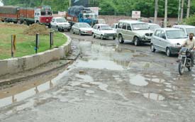 Vehicles painstakingly make their way through the potholes around the roundabout while entering Jalandhar near Rama Mandi. 