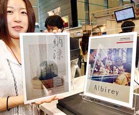An employee of Japan's electronics giant Hitachi displays a new A4-paper-sized 4,096-color electric paper display "Albirey", which is 3.7mm thick and works on ultra-low electric consumption, at Hitachi's high-tech convention in Tokyo on Wednesday. 