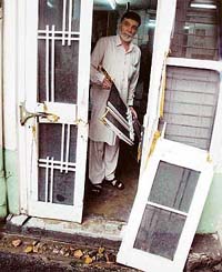 Mr Harish Kumar shows the broken door and damage caused by two bulls in his house near Kailash Nagar in Ludhiana