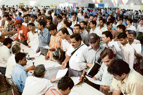 People wait for their turn on the last day of filing income tax returns at Pragati Maidan in New Delhi on Monday.