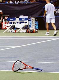 Andre Agassis racquet lies broken on the court after Agassi, top right, threw it down in his match against Andrea Stoppini of Italy at the Legg Mason Tennis Classic in Washington