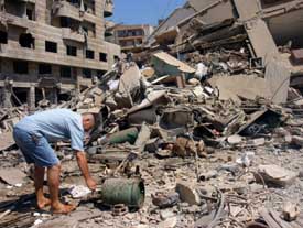 A Lebanese man removes gas canisters from the ruins of his house destroyed during an overnight Israeli air raid on Beiruts suburbs. Many buildings were flattened duriing the attack on Saturday