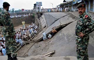 Pakistani army soldiers stand guard as rescue workers search for missing bodies at the site where a bridge collapsed in Mardan, about 50 km west of Peshawar, on Sunday.