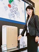 An employee of Japan's electronics giant Sharp displays a new line of air purifiers known as KC-51C1 in Tokyo