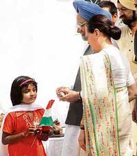 AICC President Sonia Gandhi and Dr Manmohan Singh distribute sweets among poor children after unfurling the Tricolour at the Congress office in New Delhi on Tuesday.