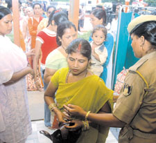 A security officer inspects the purse of a devotee in a temple on the occasion of Janmashtami in the Capital on Wednesday