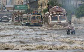 Vehicles drive down a flooded street in Karachi