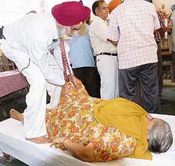 Dr Amrik Singh Kapur, inventor of the Kapur Reflexochiro Drug-Free Cure and author of Stop the Pain, examines a patient during a free check-up camp at the Chandigarh Press Club on Saturday