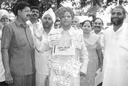 A former BJP MP, Mr Ratan Lal Kataria, wears a garland of scams, which took place during various Congress governments, in Ambala on Saturday.