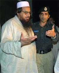 A Pakistani police officer escorts Hafiz Mohammad Saeed outside his residence in Lahore late on Monday night.