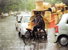 Intermittent rains brought traffic flow to a snail's pace in Delhi on Saturday as this scene shows, with a cyclist laden with reed baskets, chairs and moorhas, making a deft attempt to wheel past the bumper-to-bumper ride.