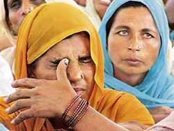 A woman wipes her tears at a public hearing on farmers suicides held in Bathinda on Thursday.